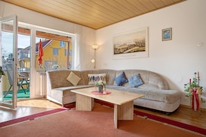 Een woonkamer met een bank, een salontafel, een lamp en een schilderij aan de muur.