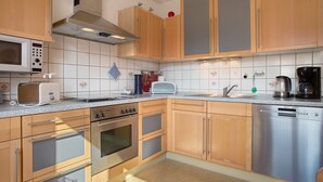 Eine Küche mit Holzschränken, einer Mikrowelle, einem Toaster, einer Kaffeemaschine und einem Geschirrspüler.