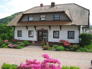 A two-story house with a tiled roof, a front door, and a small porch.