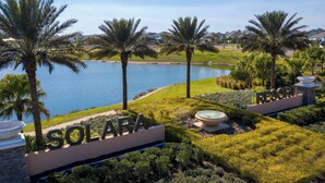 A resort named Solara with a view of a lake, palm trees, and a well-maintained lawn. - Epic Luxury Villa near Disney, Game Rooms & Pool (Kissimmee)
