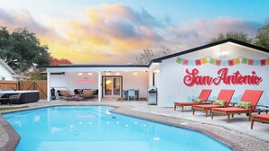Un espace piscine avec des chaises longues, un barbecue et un bâtiment portant l’inscription « San Antonio ».