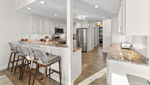 A modern kitchen with white cabinets, stainless steel appliances, and a marble countertop. - Luxury Beachfront Retreat~Pool~Game Room~Sleeps 16 (Bradenton)