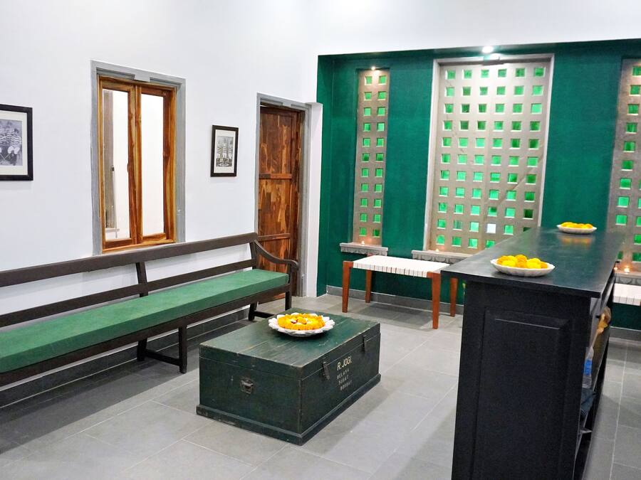 Une pièce avec un banc en bois, une petite table sur laquelle se trouve une assiette de fruits, un meuble vert et une cloison verte.