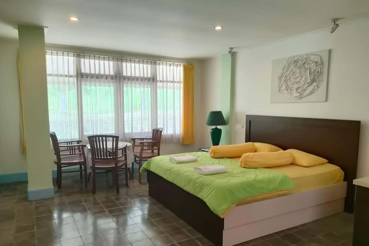 Ein Hotelzimmer mit einem Bett, einem Schreibtisch, Stühlen und einem Fenster mit Vorhängen.