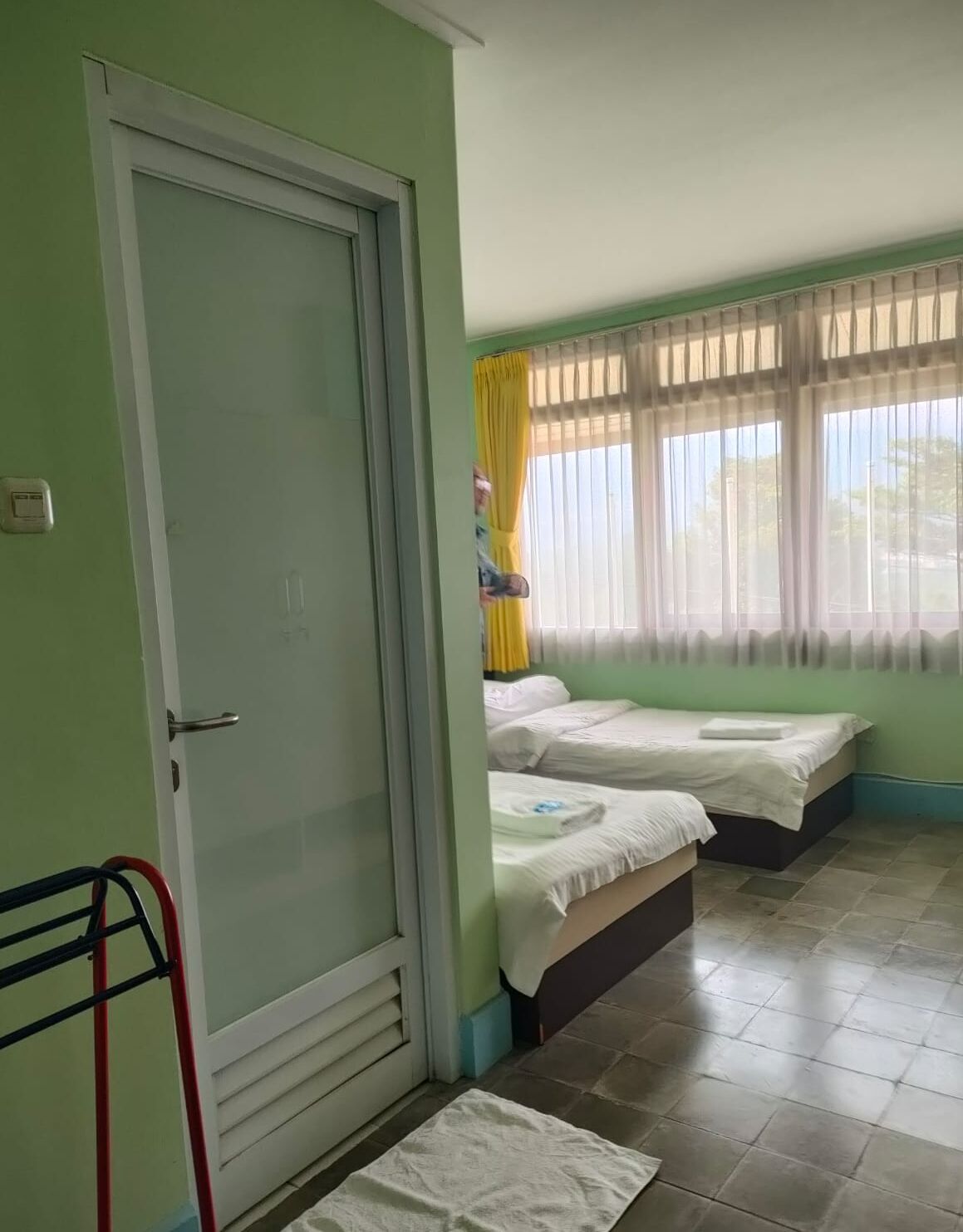 A room with two beds, a door, and a window with curtains.