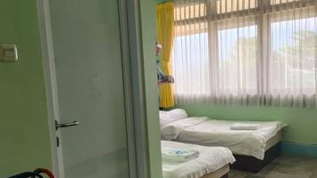 A room with two beds, a door, and a window with curtains.