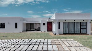 Una casa moderna de dos pisos con techo plano, grandes puertas correderas de vidrio y un césped bien cuidado.