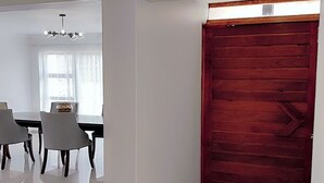 Una habitación amplia con comedor, una puerta grande de madera y un candelabro.