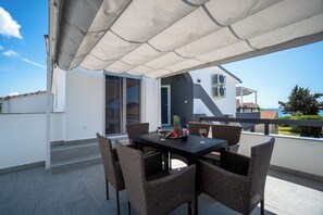 An outdoor patio with a table and chairs, a bottle of wine, and a fruit plate. - Villa Skundric (Vir)
