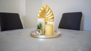 A table with a decorative centerpiece featuring a golden leaf, a small potted plant, and a golden candle. - Villa Skundric (Vir)