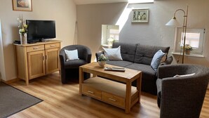 A living room with a TV, sofa, chairs, a coffee table, and a skylight. - Apartment 'Uhlenhoff Boyken' with Private Terrace, Shared Garden and Wi-Fi (Apen-Bokelermoor)