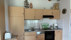 A kitchen with wooden cabinets, a stainless steel sink, a coffee maker, and a toaster. - Apartment 'Uhlenhoff Boyken' with Private Terrace, Shared Garden and Wi-Fi (Apen-Bokelermoor)