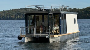 A houseboat with a deck, a small enclosed area with a table and chairs, and a view of the water. - Houseboat 'Kitilou' with Lake View, Private Terrace, and Wi-Fi (Dobin)