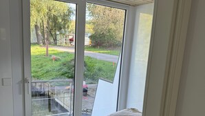 A bedroom with a bed, a sliding glass door leading to an outdoor area with greenery and a pathway. - Houseboat 'Kitilou' with Lake View, Private Terrace, and Wi-Fi (Dobin)