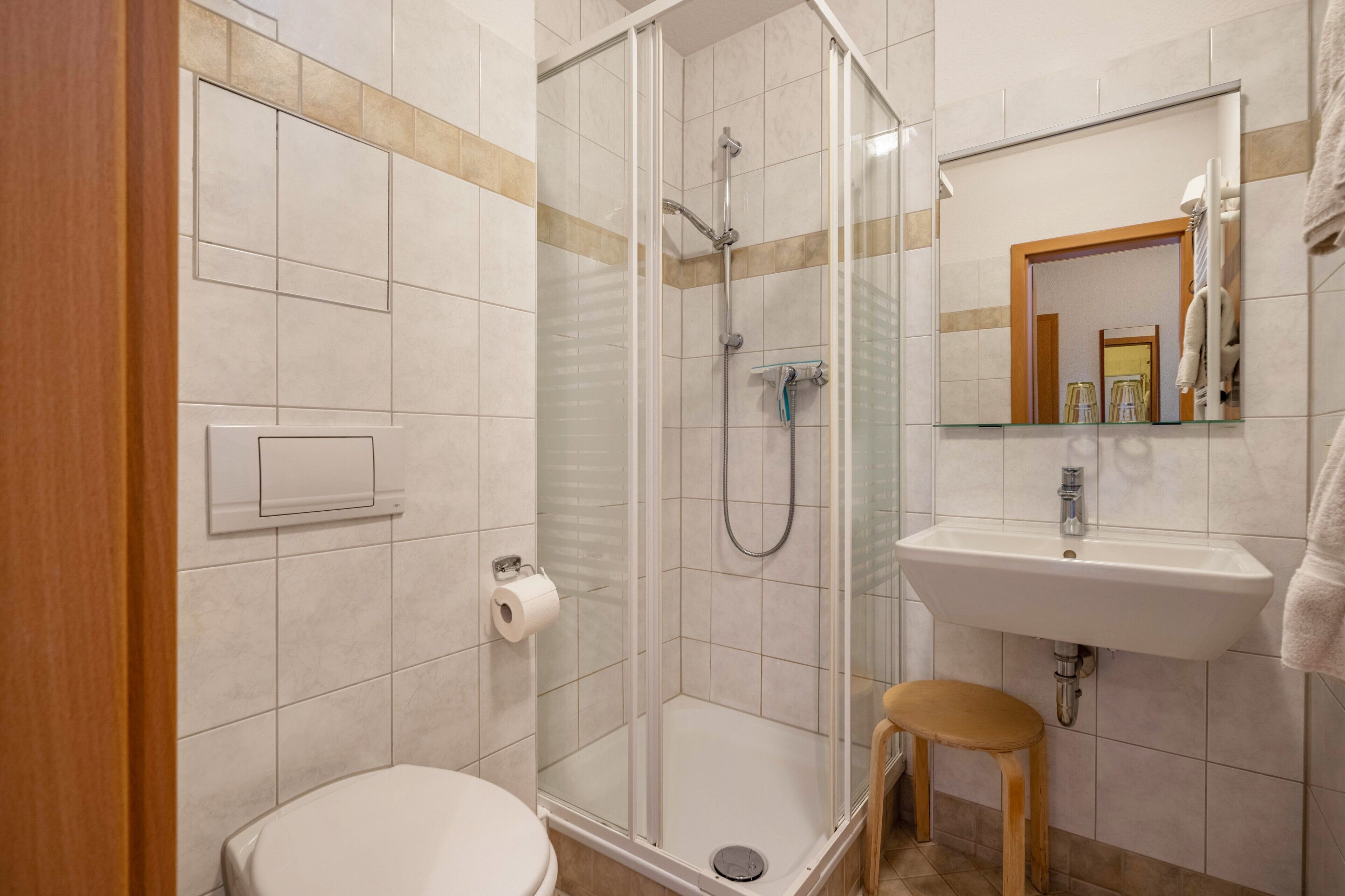 Un baño con ducha envuelta en vidrio, lavabo, inodoro y espejo.