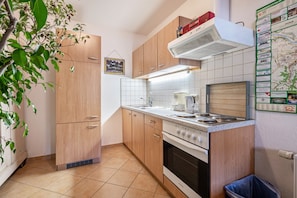 A compact kitchen with wooden cabinets, a stove, and a wall-mounted map. - Room 'Doppelzimmer 1' with Shared Terrace and Wi-Fi (Meißen)