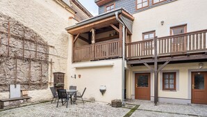 A building with a balcony, a stone wall, and a wooden fence.