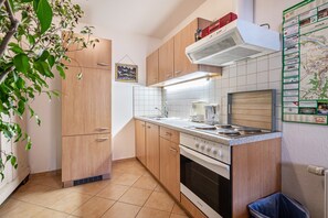 Una cocina compacta con armarios de madera, una estufa y un mapa colgado en la pared.