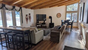 A cozy living room with a wooden ceiling, a fireplace, a TV, and a dining area with a table and chairs. - Key Condo 2934a (Keystone)