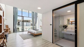Une chambre moderne avec un grand lit, un bureau et un balcon agrémenté de rideaux.