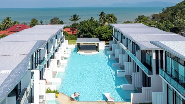 Un hôtel moderne doté d’une piscine centrale et offrant une vue sur la mer et les montagnes.