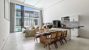 Une cuisine moderne avec des armoires blanches, un pare-feu en marbre et un coin repas avec des chaises en bois et une table dressée pour quatre personnes.