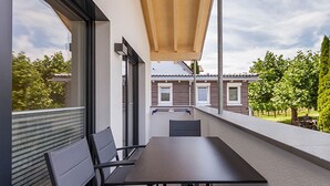 A balcony with a table and chairs, large windows, and a view of a residential area. - Apartment '302' with Shared Garden, Wi-Fi and Air Conditioning (Hagnau)
