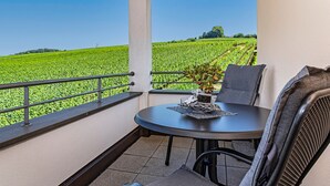 A balcony with a table and chairs, overlooking a green field. - Room '205' with Shared Garden, Balcony and Wi-Fi (Hagnau)