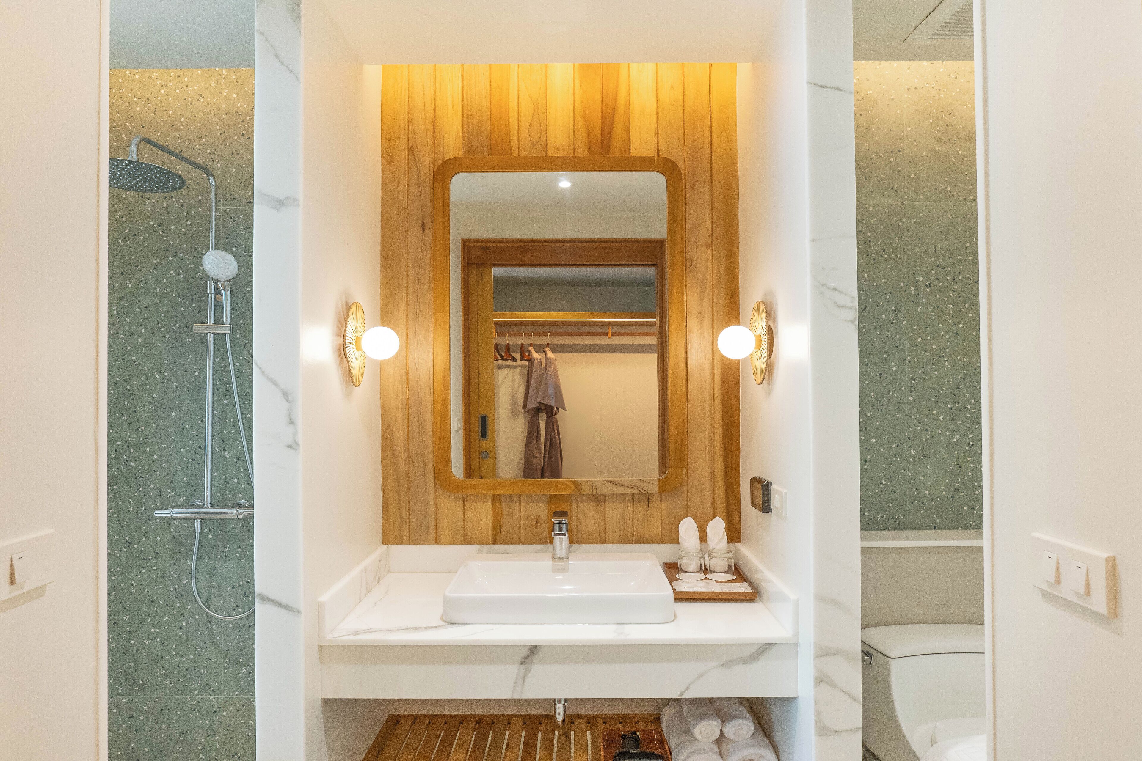 Une salle de bain avec un meuble-lavabo en bois, un miroir, une douche et des toilettes.