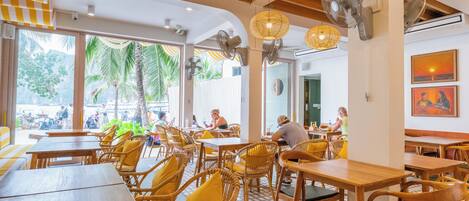 A restaurant with wooden tables and chairs, large windows, and fans on the ceiling.