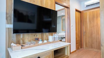 Un baño moderno con un espejo grande, tocador de madera y televisor de pantalla plana.