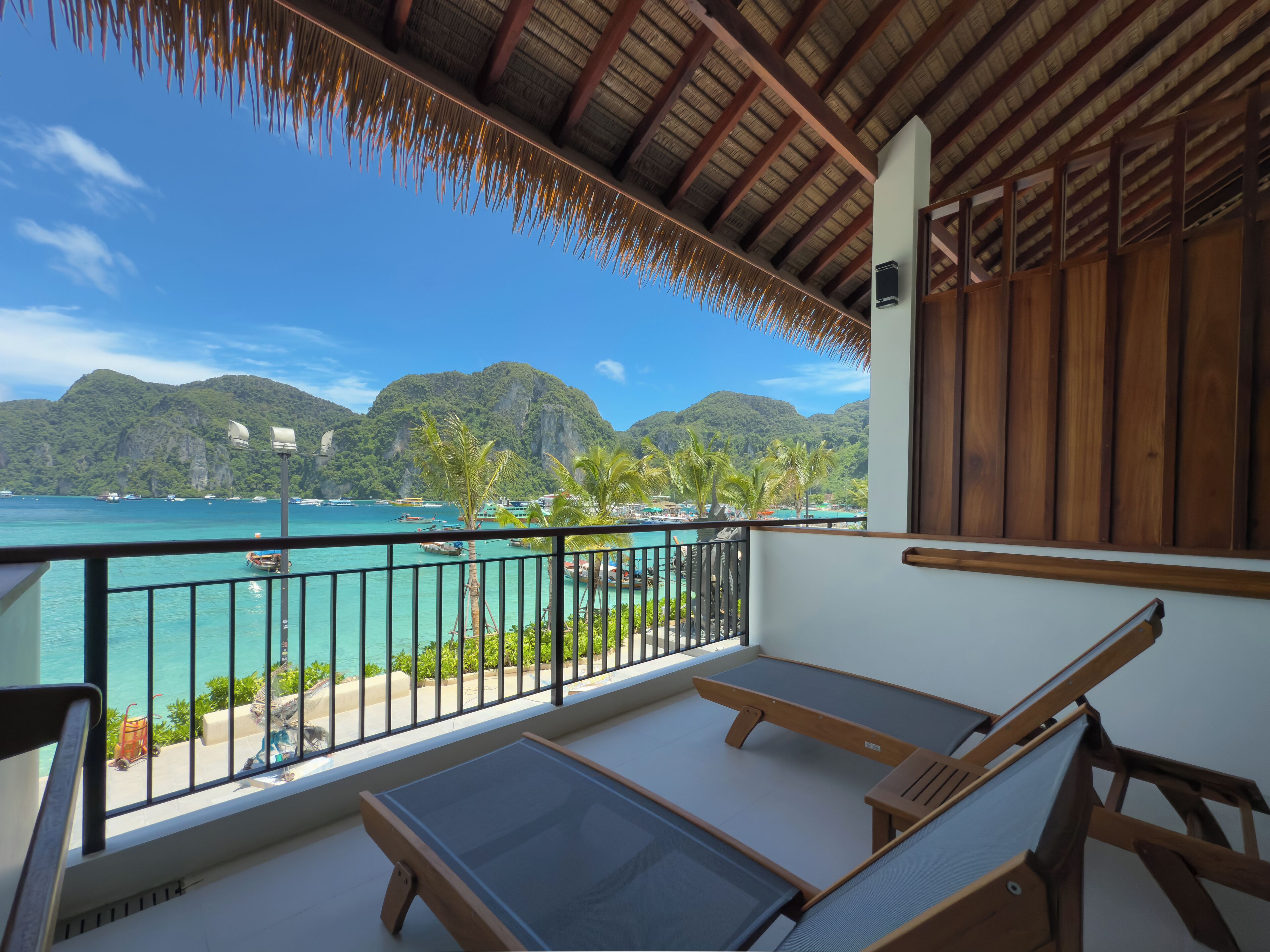 A balcony with a view of turquoise waters and a mountainous landscape.