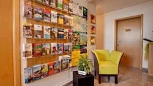 A hotel lobby with a bookshelf filled with travel books, a yellow armchair, and a door labeled '103'. - Room '102' with Shared Garden, Balcony and Wi-Fi (Hagnau)
