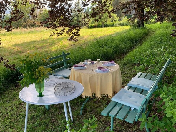 Un espace extérieur aménagé pour les repas, avec une table ronde, des chaises et un banc.