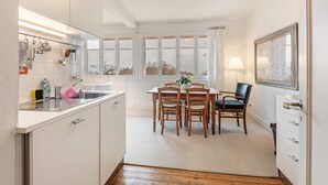 A kitchen with a sink, cabinets, and a dining area with chairs and a table. - Apartment 1 with Alpine Views, Outdoor Seating, and Wi-Fi (Schopfheim)