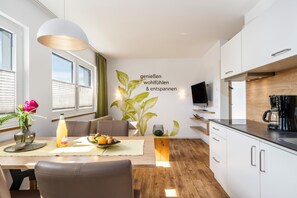 Una cucina moderna con mobili bianchi, un piano di lavoro in legno e un piano cottura integrato.