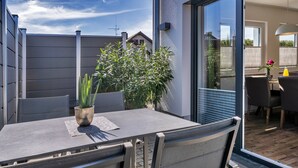 Une terrasse extérieure avec une table, des chaises et un pot de fleurs.