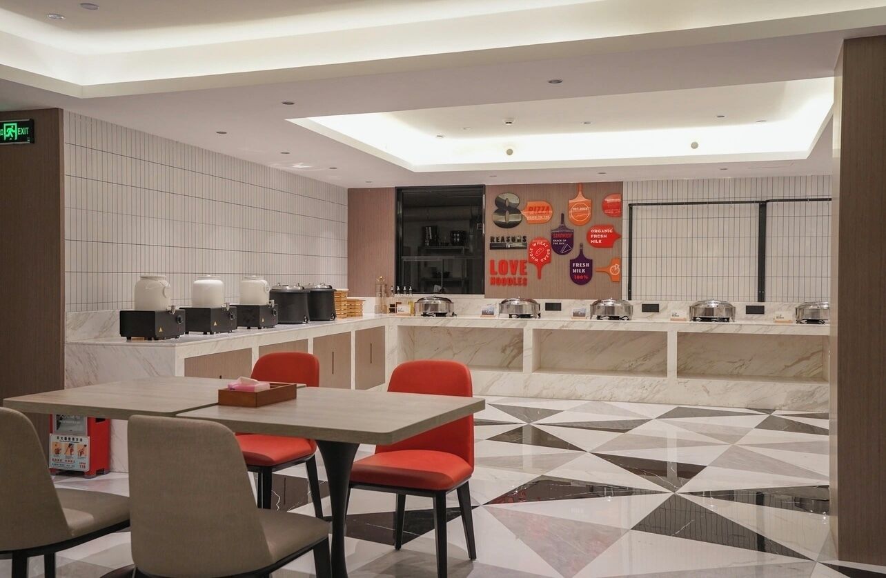 A modern restaurant with a central counter, seating area, and a patterned floor.