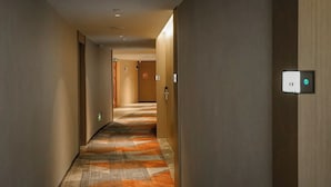 Un pasillo de hotel con alfombra estampada, paredes de madera y una puerta al final.