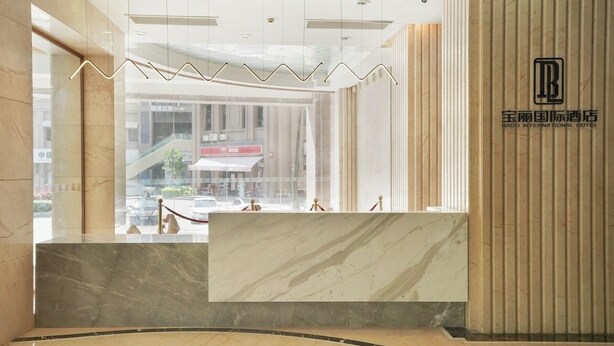 Un mostrador de recepción de mármol con un logotipo, vista a un centro comercial y un diseño de interiores moderno.