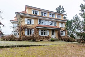 A two-story building with a stone-paved front yard, multiple windows, and a red-tiled roof. - Vacation apartment '2' with mountain view, private balcony and Wi-Fi (Schopfheim)