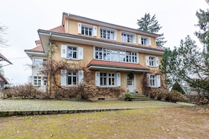 A two-story building with a stone-paved front yard, multiple windows, and a red-tiled roof. - Vacation home 'Maisonette 1c' with mountain view, private balcony and Wi-Fi (Schopfheim)