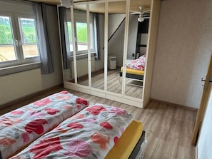 Una camera da letto con un letto, un armadio, un termosifone e una finestra con tende.