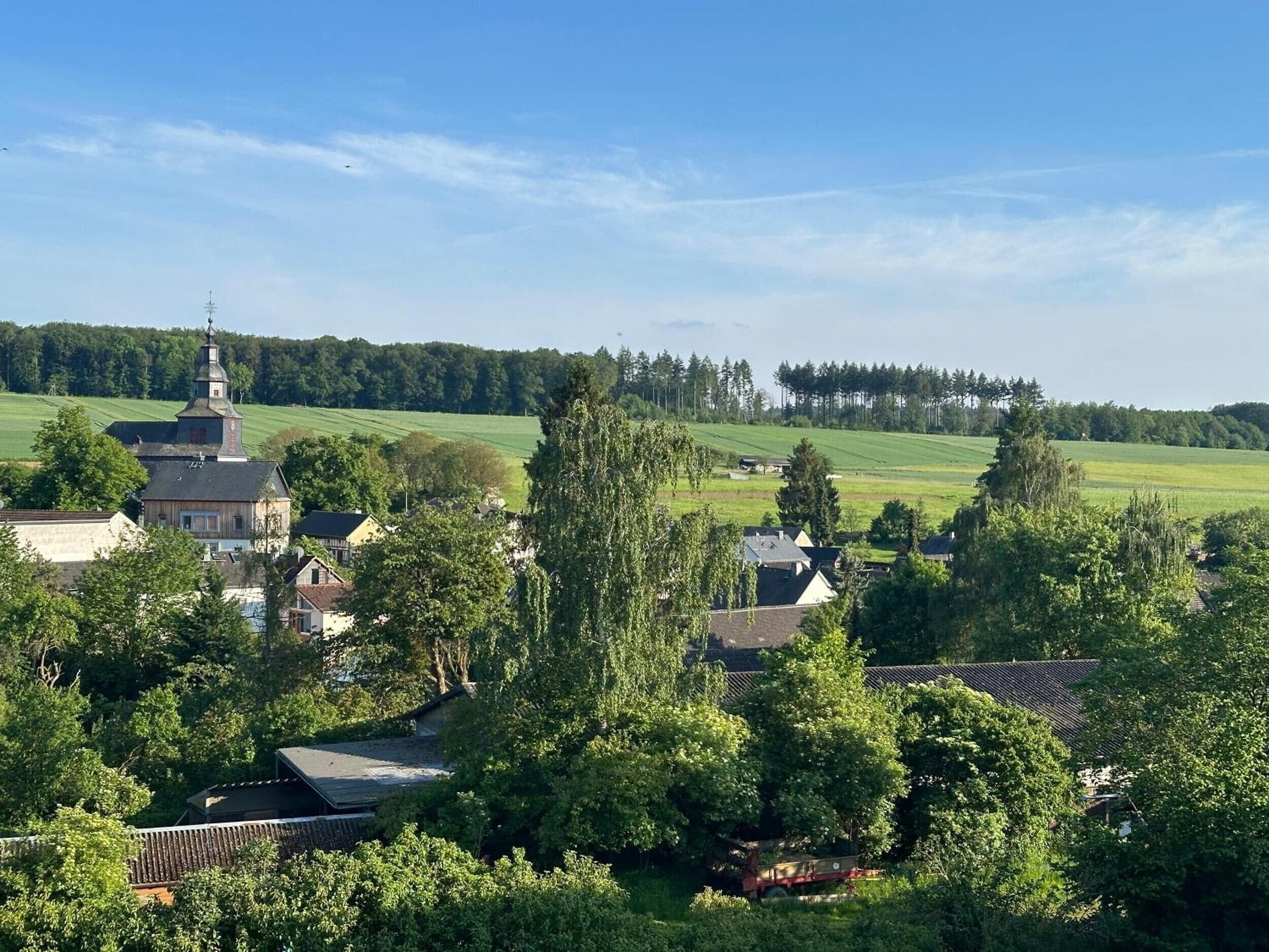 Ein ländliches Dorf mit Kirche, Häusern und Feldern ringsum.