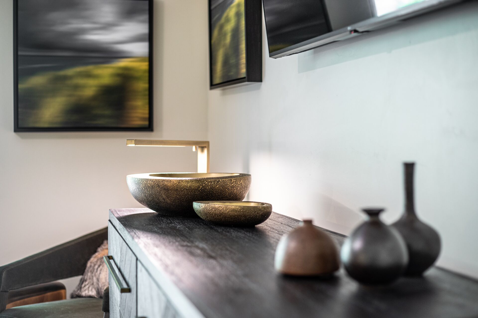 Een moderne badkamer met een donker houten wastafelmeubel, een groot stenen wastafel en een kleine vaas.