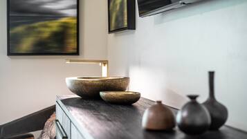 Een moderne badkamer met een donker houten wastafelmeubel, een groot stenen wastafel en een kleine vaas.