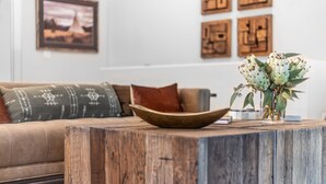 A living room with a wooden coffee table, a sofa with patterned cushions, and a vase with green plants.