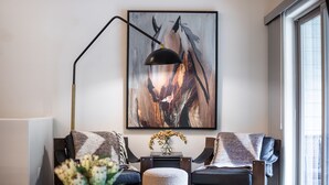 A modern living room with a sofa, a floor lamp, and a large abstract painting.