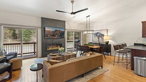 A spacious living room with a fireplace, a dining area, and a kitchen.