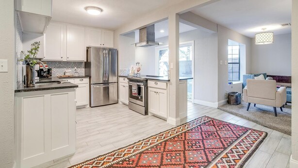 A modern kitchen with white cabinets, stainless steel appliances, and a patterned rug. - The Westside Collective (Westworth Village)